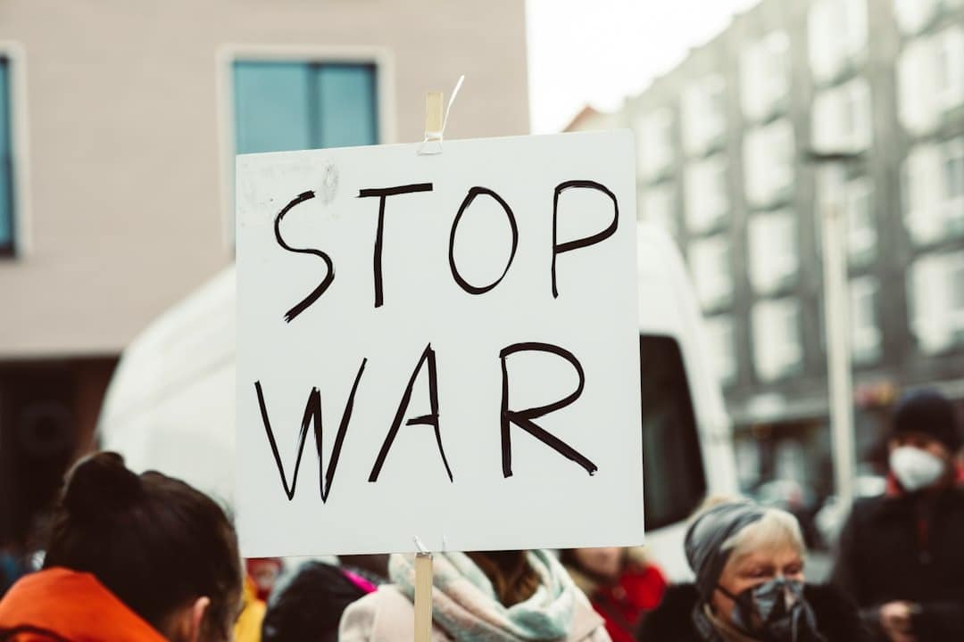 White protest sign with "STOP WAR" in black letters.